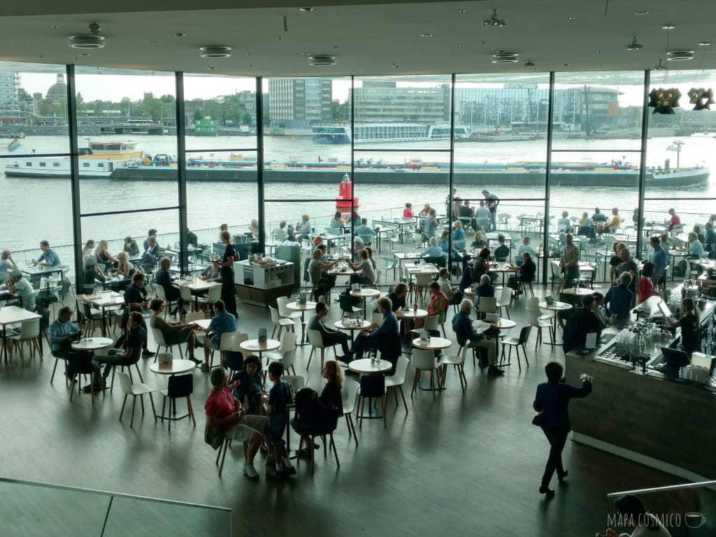 café panorámico del EYE museum en Ámsterdam,  haymuchísimas mesas adentro y afuera con vista al río